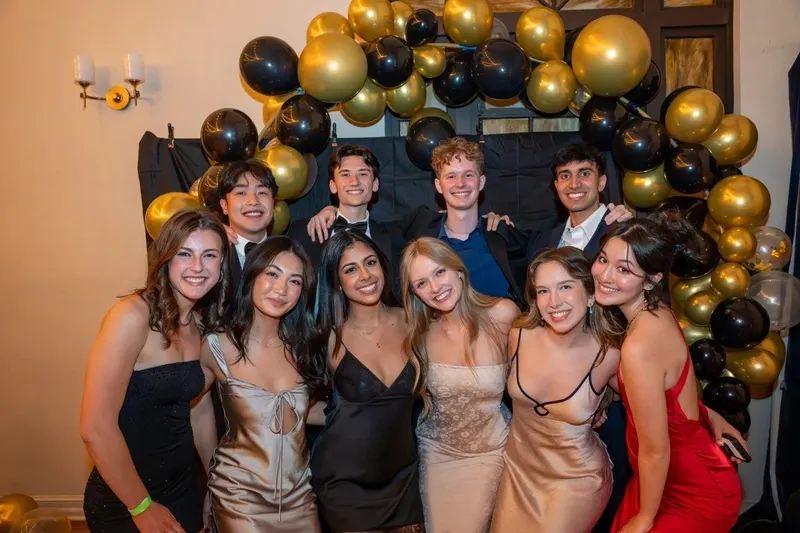 Brothers posing in front of black and gold balloons at the 10th Annual Banquet