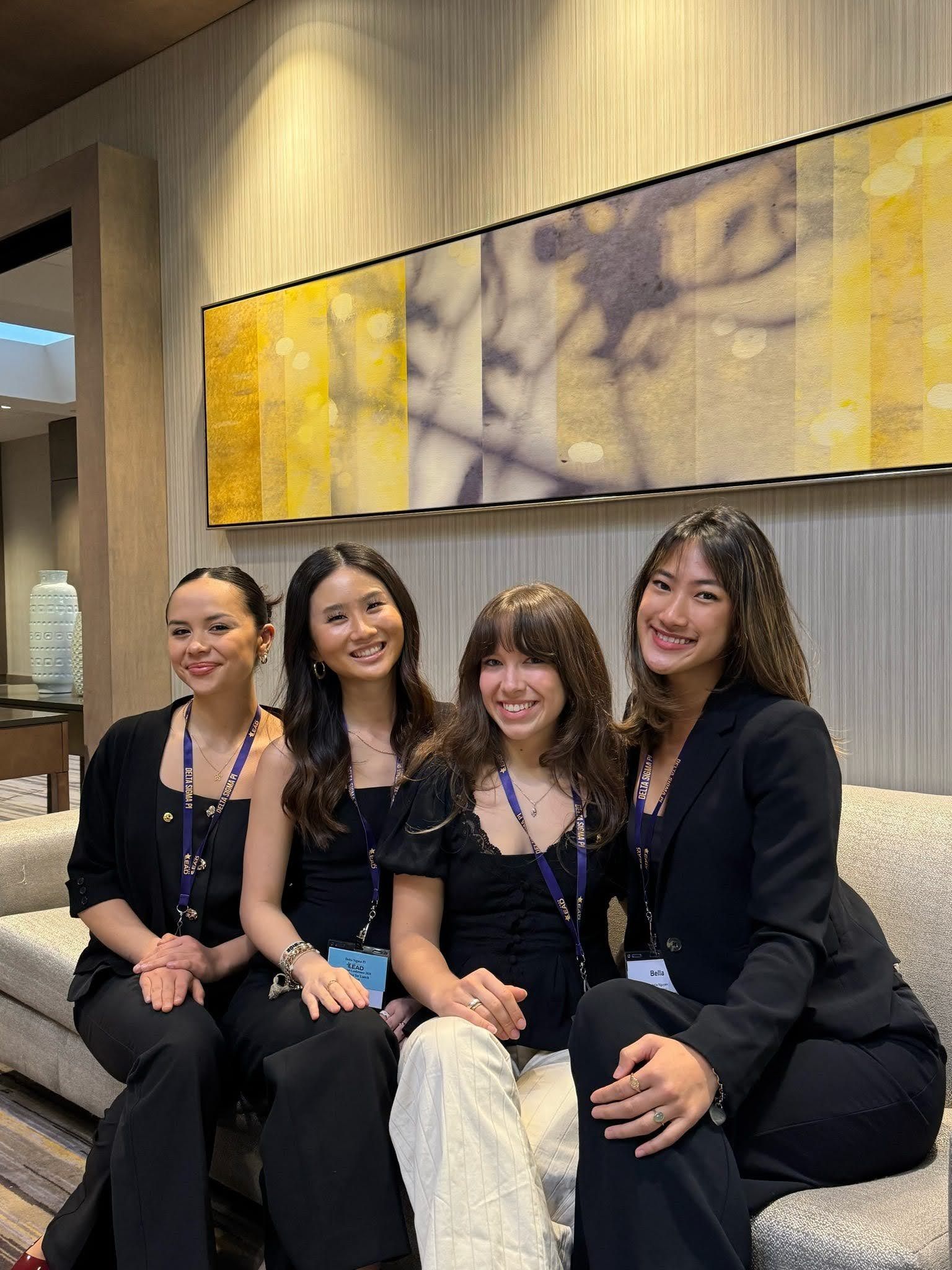 Four brothers in business attire with LEAD conference lanyards seated on a lounge sofa