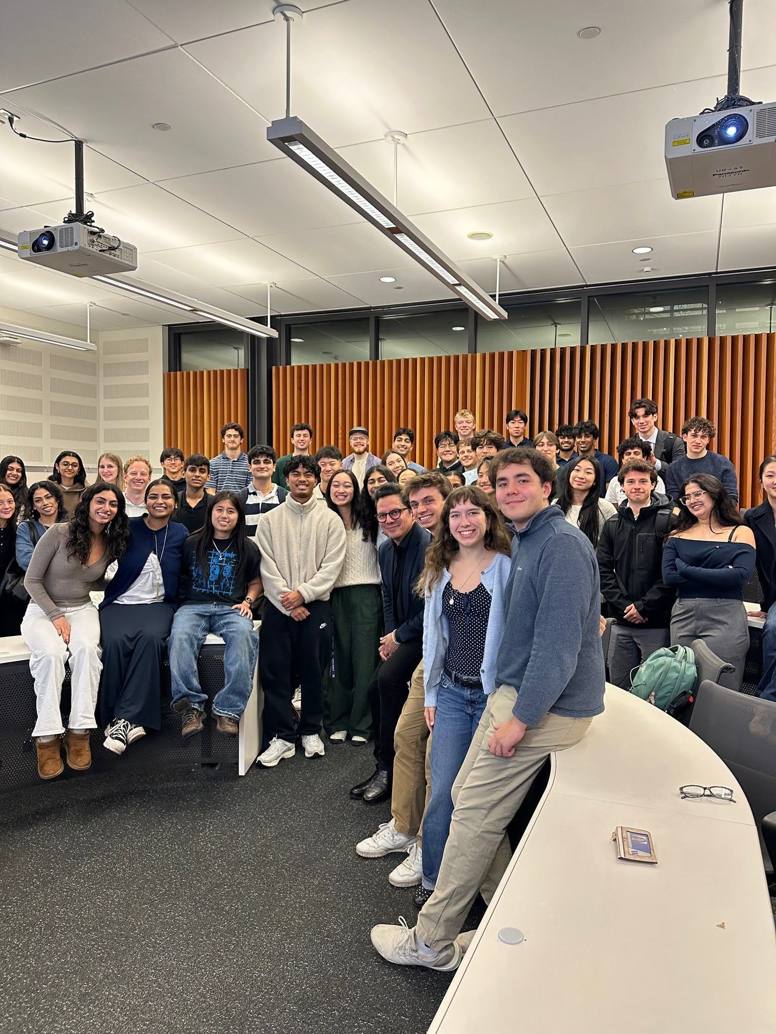 Brothers and guests gathered at the front of a lecture hall after a speaker event