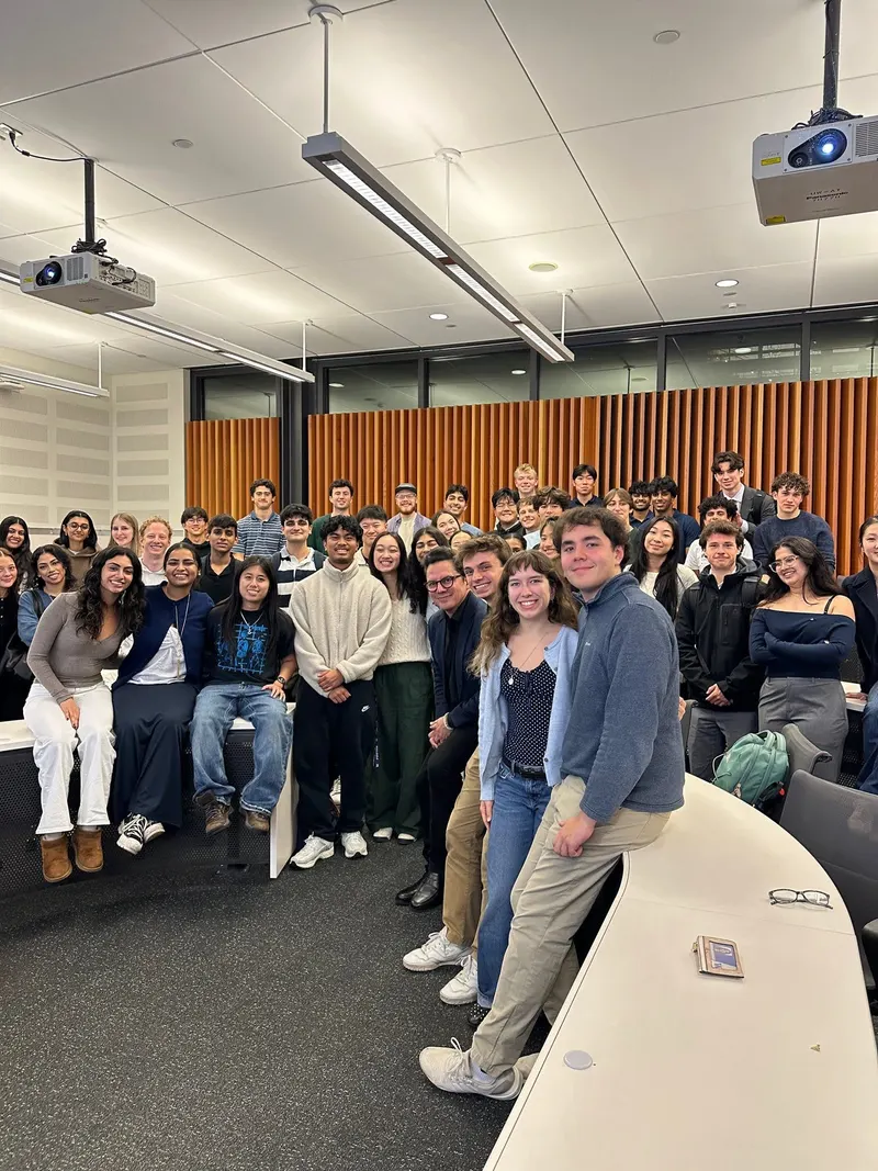 Brothers and guests gathered at the front of a lecture hall after a speaker event