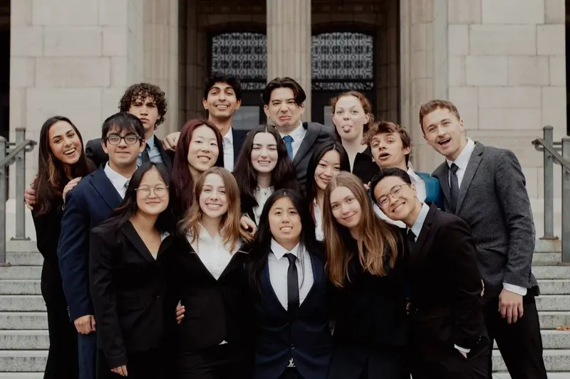 The Chi Class in business attire on the steps of a campus building