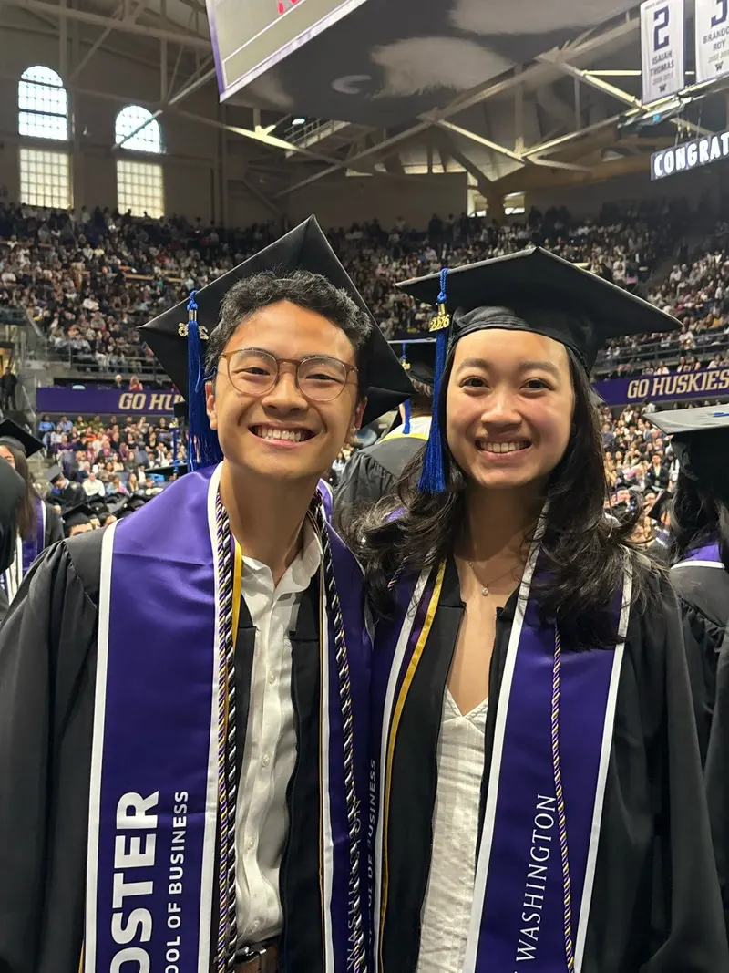 Two graduating brothers in caps, gowns and Foster School of Business stoles at the Foster graduation ceremony