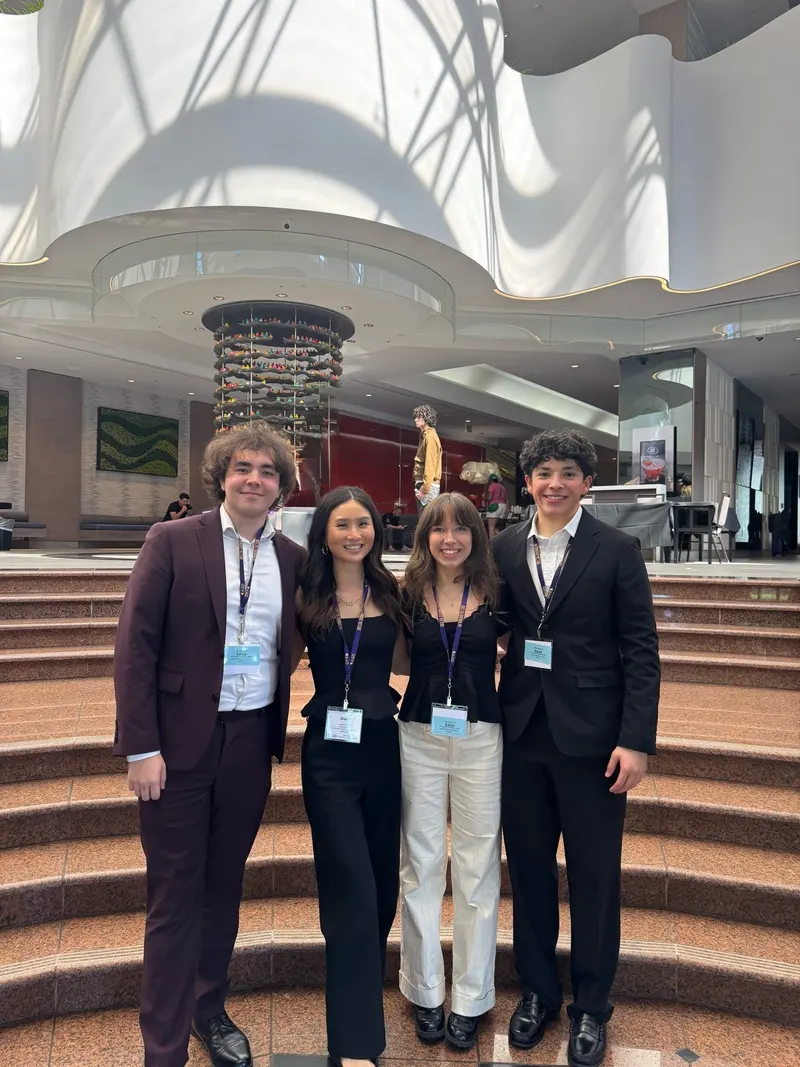 Four brothers in business attire with LEAD conference lanyards on the steps of a hotel lobby