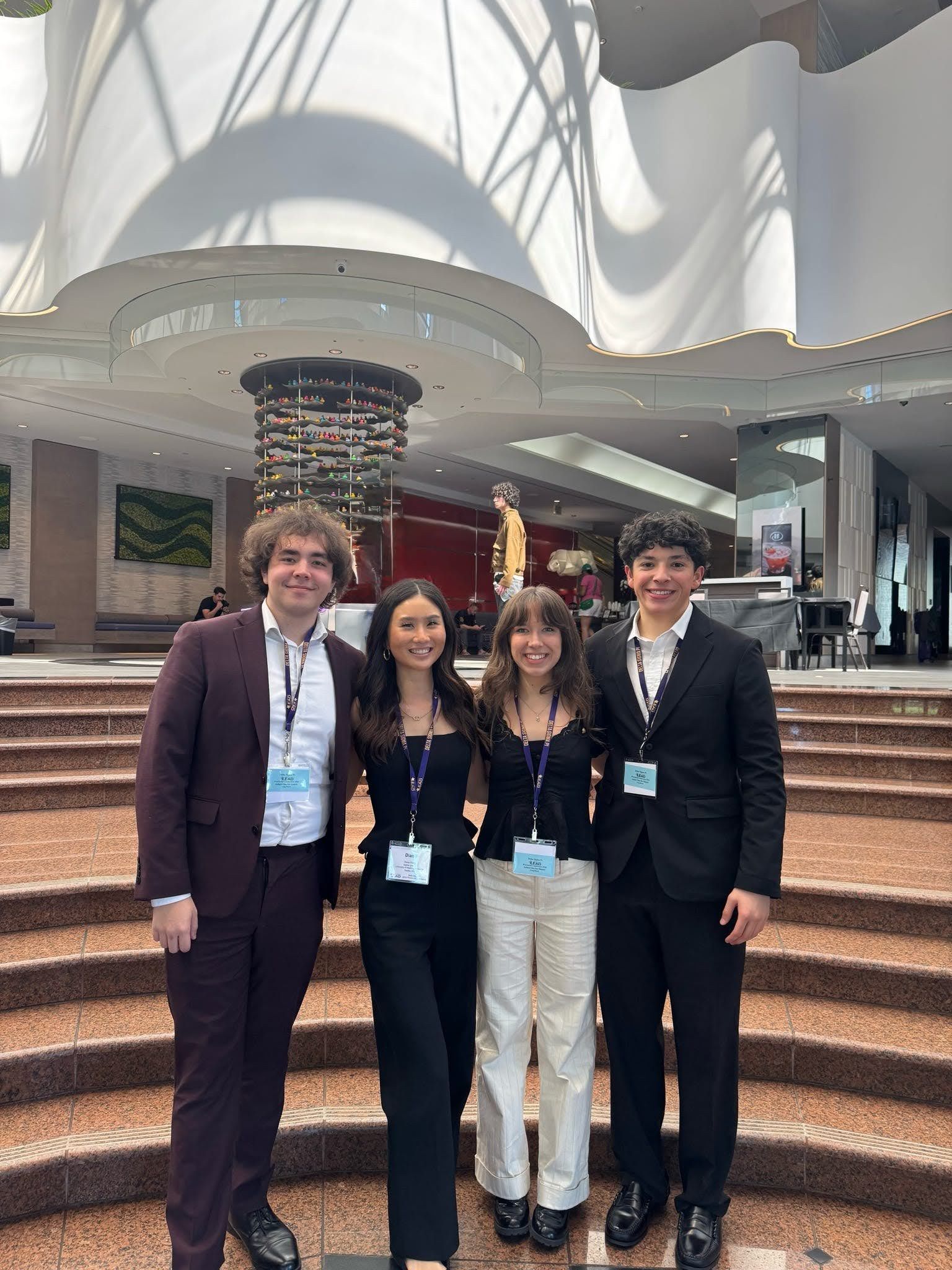 Four brothers in business attire with LEAD conference lanyards on the steps of a hotel lobby