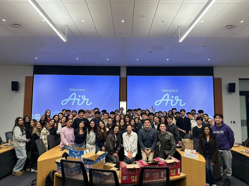 Brothers posing in a lecture hall under a Welcome to Air slide